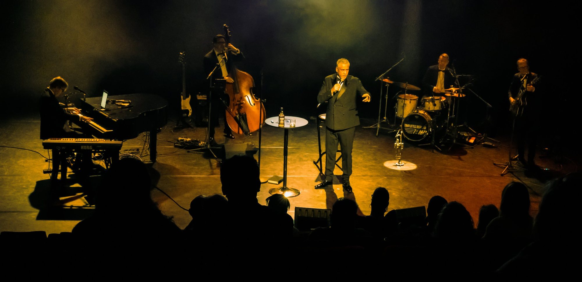 TinyLittleBigBand on stage in warm light: piano with an iPad, double bass, singer, drums and guitar