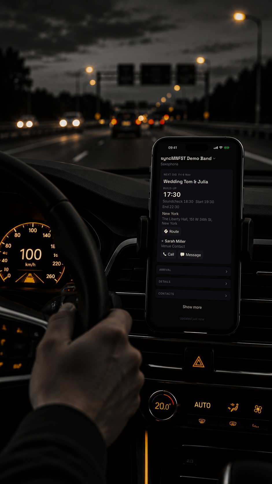 iPhone in a dashboard mount showing the next gig in syncMNFST, motorway at dusk